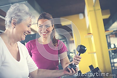 Trainer working exercise with senior woman in the gym. Stock Photo