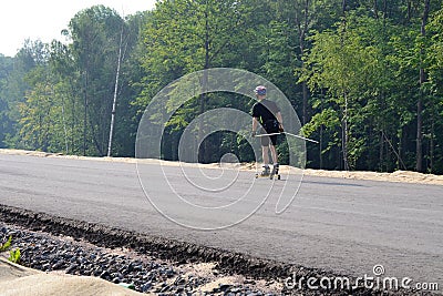 Training an athlete on the roller skaters. Biathlon ride on the roller skis with ski poles, in the helmet. Autumn workout. Roller Editorial Stock Photo