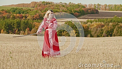Training in the autumn field - a belligerent woman wields with a sword Stock Photo