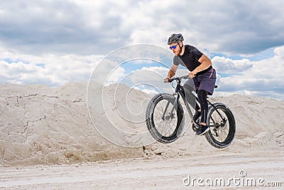 Training a bicyclist in a chalky quarry. A brutal man on a fat bike. Stock Photo