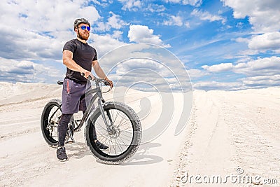 Training a bicyclist in a chalky quarry. A brutal man on a fat bike. Stock Photo