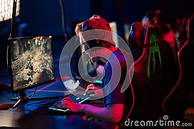 Training bootcamp for professional esports players. Young cyber-athletes play an online shooter game. Glowing keyboard Stock Photo