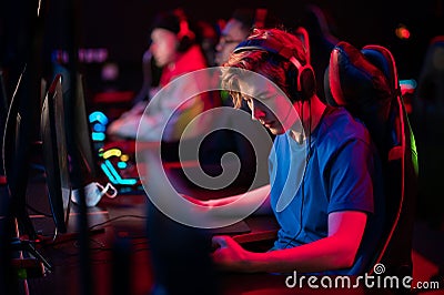 Training bootcamp for professional esports players. Young cyber-athletes play an online shooter game. Glowing keyboard Stock Photo