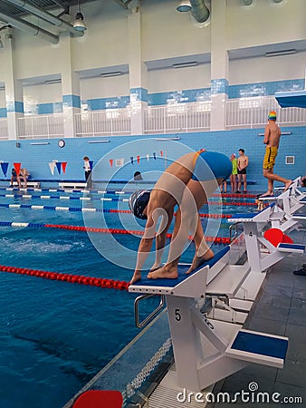 Training swimmers. A teenage boy is preparing to jump into the pool. Sport is a way of life. Health, good figure and Editorial Stock Photo