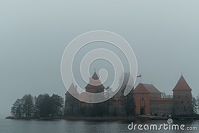 Trakai Island Castle - turreted castle on a tranquil island connected by footbridge with a Lithuanian culture museum during foggy Stock Photo