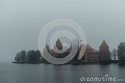 Trakai Island Castle - turreted castle on a tranquil island connected by footbridge with a Lithuanian culture museum during foggy Stock Photo