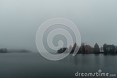 Trakai Island Castle - turreted castle on a tranquil island connected by footbridge with a Lithuanian culture museum during foggy Stock Photo