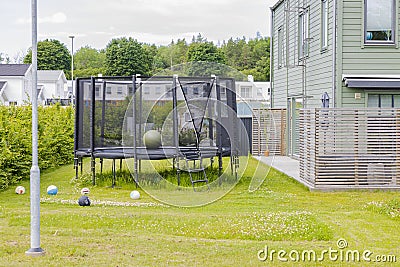 Trampoline with safety net mounted on backyards with football balls. Outdoor activity concept. Stock Photo