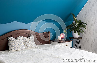 Tranquil blue color bedroom concept. Air cleaning plant Spathiphyllum on flower stand Amethyst crystal lamp illuminated. Stock Photo