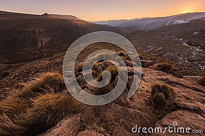 A tranquil golden snow-covered rocky mountain landscape taken at sunset Stock Photo