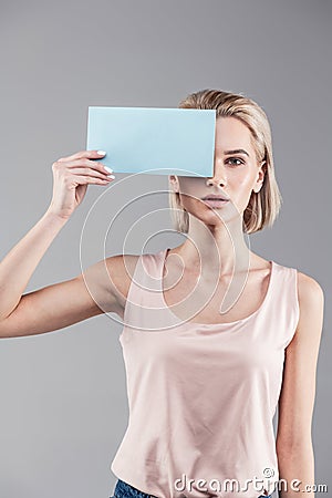 Tranquil neutral woman with blonde short hair wearing nude shirt Stock Photo