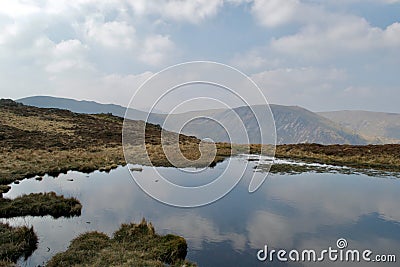 Tranquil reflections of the sky in a mountain lake tarn Stock Photo