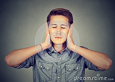 Tranquil, relaxed young man covering ears, eyes closed Stock Photo