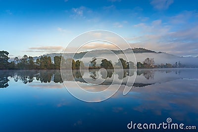 Tranquil sunrise landscape with perfect reflection of sky and trees in lake Stock Photo