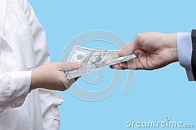 Transfer of a bundle of 100 dollar bills to a female doctor on a blue background. Concept: a bribe to a doctor, payment for treatm Stock Photo