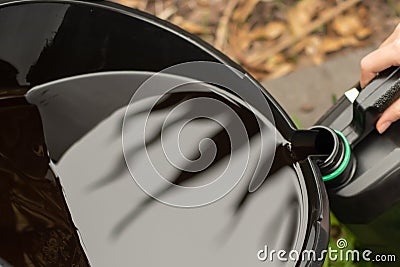 Transfering of used drained motor oil from the black tray to the empty container. DIY change engine motor oil Stock Photo