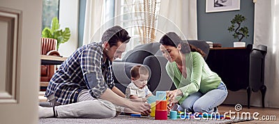 Transgender Family With Baby Playing Game With Colourful Toys In Lounge At Home Stock Photo