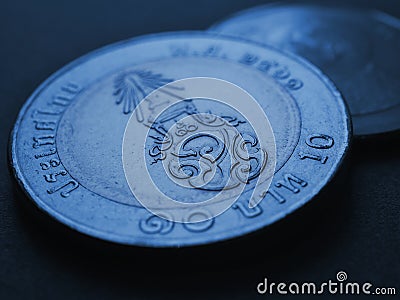 Translation: 10 baht Thailand. Thai coin dark background. News about money or currency. Loan and credit. Tax and inflation. Blue Stock Photo