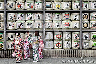 Translation: girls in kimono in front of drums or barrels of sake (Japanese alcoholic drinks) at Tsurugaoka shrine Editorial Stock Photo