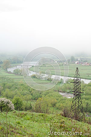 Transmission tower. Giant cloud. Bridge over river. Foggy weather. Carpathians, Ukraine. Stock Photo