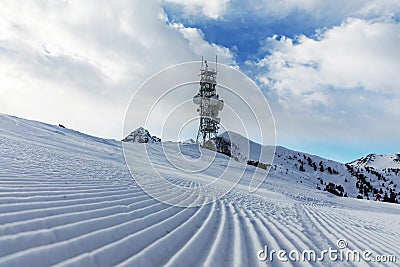 A transmitter at the top of a mountain in the Dolomites ski area. Empty ski slope in winter on a sunny day. Prepare ski slope, Alp Stock Photo