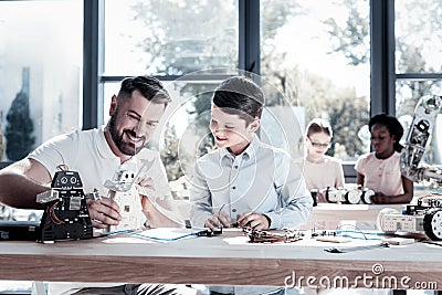 Joyful teacher and student smiling while working on robotic machine Stock Photo