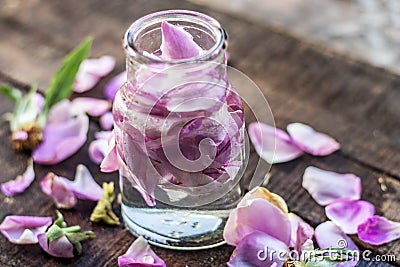 A transparent bottle contains rose water with rose petals in it Stock Photo