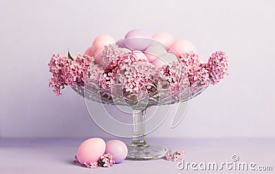 Transparent bowl with Easter eggs and flowers of Lilac on pale light violet background. Easter decor Stock Photo