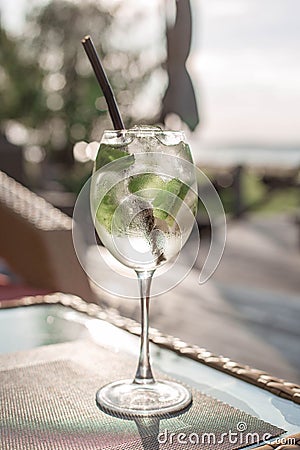 Transparent cocktail with bubbles and lime on the table at the sunset. Atmospheric summer drink in the front light close up. Stock Photo
