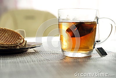 Transparent cup with brewed tea bag is on the table next to the plate Stock Photo