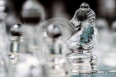 transparent glass chess on dark background, selective focus on horse piece, close-up Stock Photo