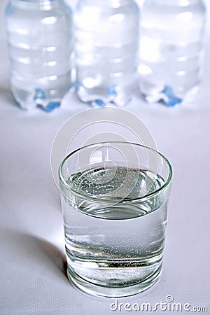 A transparent glass full of water. near a bottle of mineral water. Stock Photo