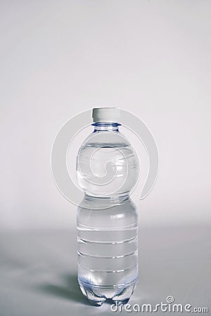 A transparent glass full of water. near a bottle of mineral water. Stock Photo