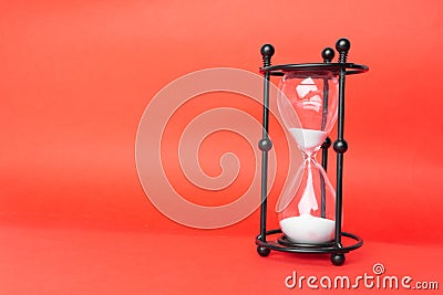 Transparent hourglass, Red background. On the right. Copy, text space Stock Photo