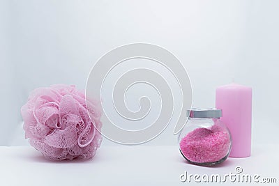 A Jar of bath salt and a candle are stand nearby. A sponge for bath stand in the left part of the photo. Light pink Stock Photo