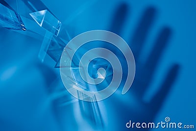 Transparent prisms and cubes with rays of the color spectrum. Abstract background with reflection and hand shadow. The concept of Stock Photo