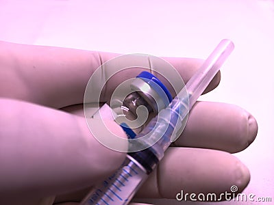 Transparent syringe with closed cap and a vaccine vial hold by doctor's hand in rubber glove Stock Photo