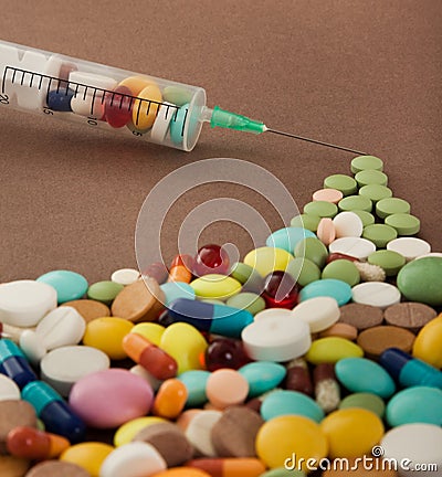 Transparent syringe collects colored tablets Stock Photo