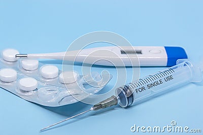 Transparent syringe, white digital electronic thermometer and white tablets in a used blister. medical treatment concept Stock Photo