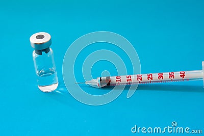 Transparent vial container with liquid medicine near small insulin syringe with capacity 1 CC and small needle on blue background Stock Photo