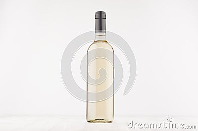 Transparent wine bottle with white wine on white wooden board, mock up. Stock Photo