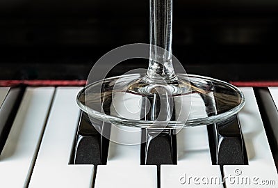 Transparent wine glass leg stand on piano keyboard Stock Photo