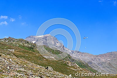 Transport helicopter flying with supplies and mountain panorama with alpine hut, Hohe Tauern Alps, Austria Stock Photo