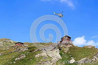 Transport helicopter flying with supplies and mountain panorama with alpine hut, Hohe Tauern Alps, Austria Stock Photo