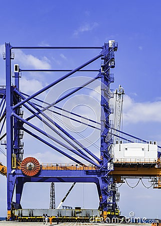 Transporting huge quay crane using self-propelled modular transporter. Moving huge quay crane from ship to harbor. Stock Photo