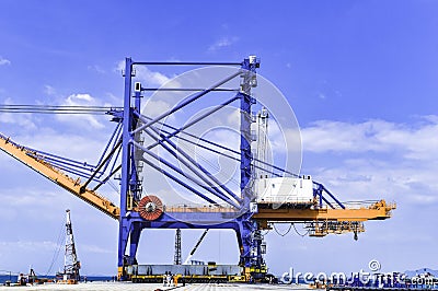 Transporting huge quay crane using self-propelled modular transporter. Moving huge quay crane from ship to harbor. Stock Photo