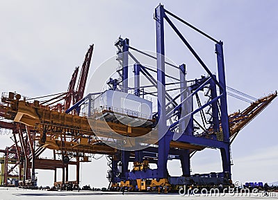 Transporting huge quay crane using self-propelled modular transporter. Moving huge quay crane from ship to harbor. Stock Photo