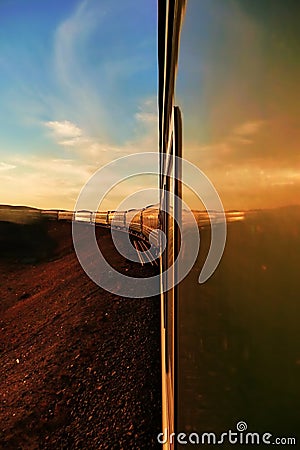 Transsiberian railway: long train making his way throught the desert in mongolia at sunset, as seen from the rear carriage. Stock Photo