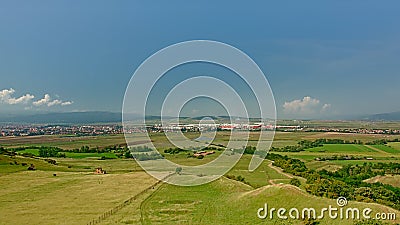 Transylvanian landscape with green meadows and city and mountains in the background Stock Photo