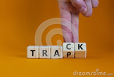 Trap or track symbol. Businessman turns wooden cubes and changes the word `trap` to `track`. Beautiful orange table, orange Stock Photo